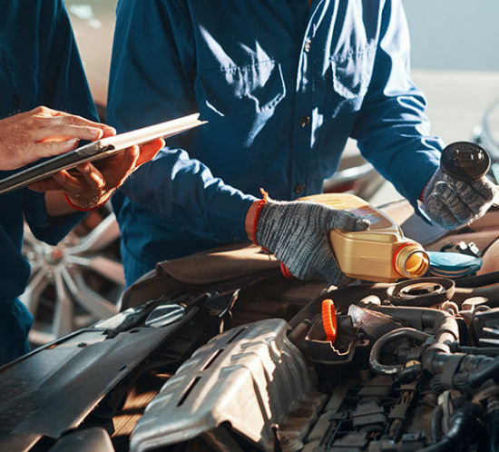 Mechanic adding oil to a car engine to promote Howard Insurance Brokers - Motor Trade Insurance