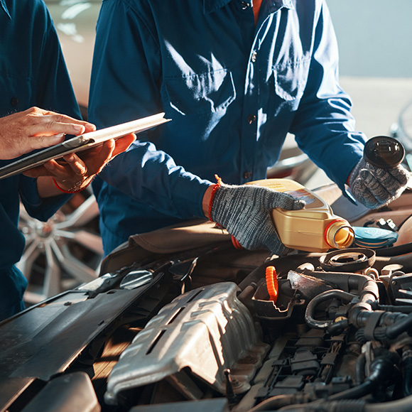 Mechanic adding oil to a car engine to promote Howard Insurance Brokers - Motor Trade Insurance