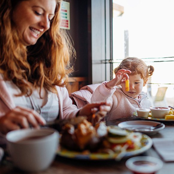 Mum and daughter tucking into a takeaway at home to promote Howard Insurance Brokers - Retail and Takeaways Insurance