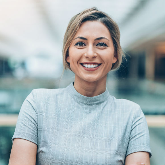 Smartly dressed smiling lady poses with arms folded to promote Howard Insurance